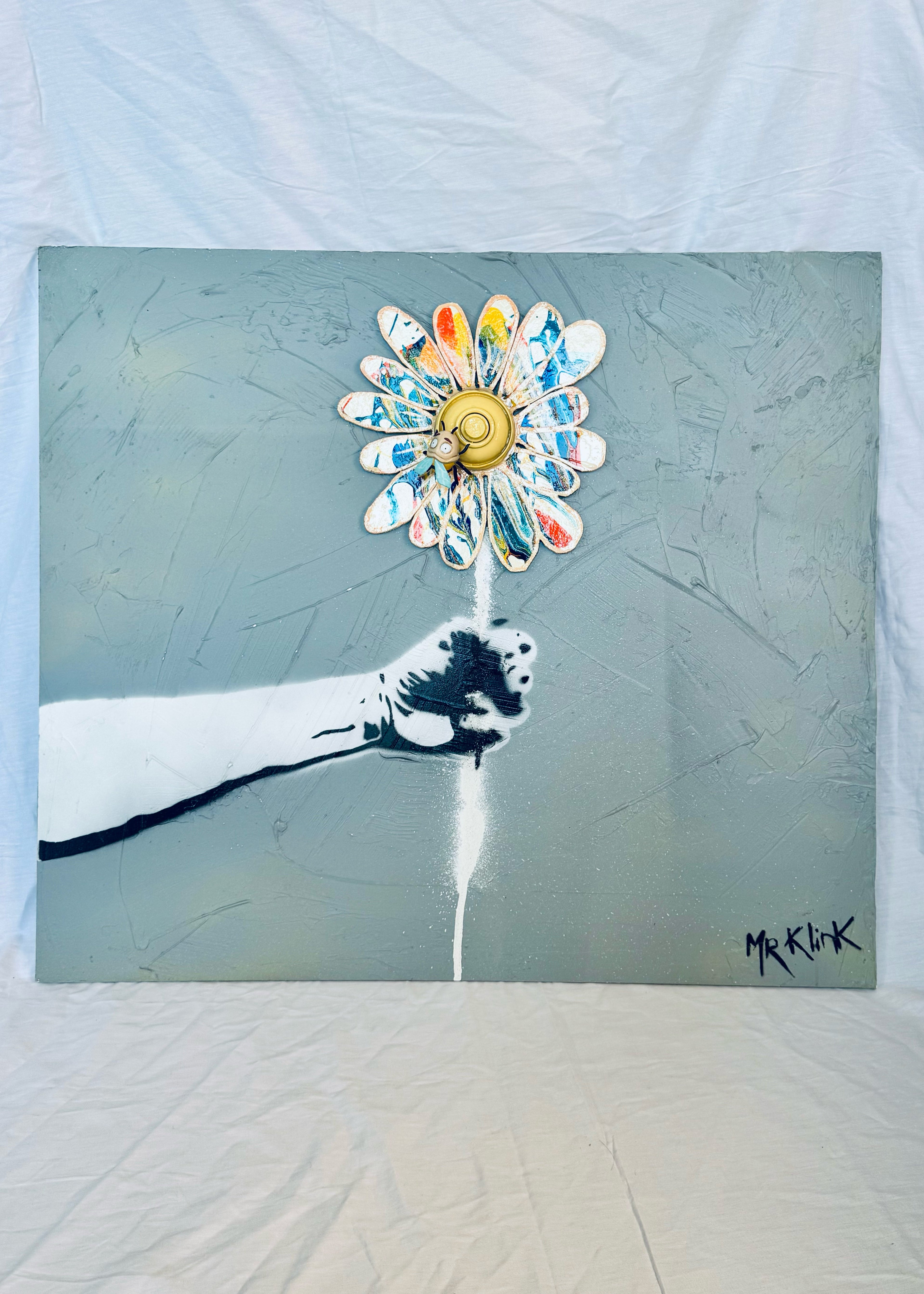 Passe-Fleur — Mr Klink, 2026. Installation street art, bras en gouttière avec fleur en bois peinte et BZzz résine.